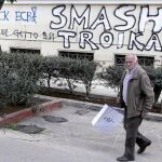 Un hombre camina junto a una pintada en el centro de Atenas