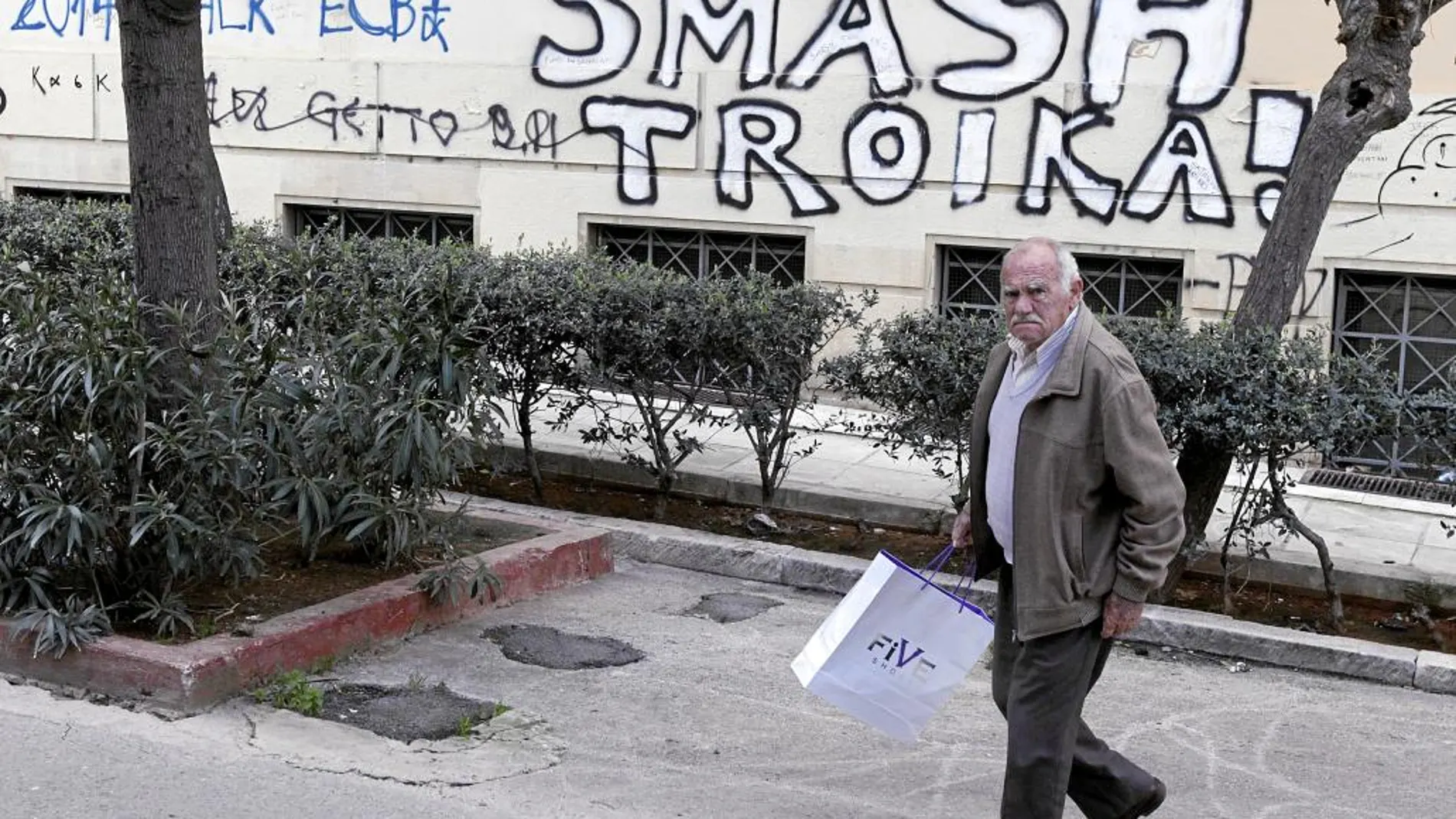 Un hombre camina junto a una pintada en el centro de Atenas