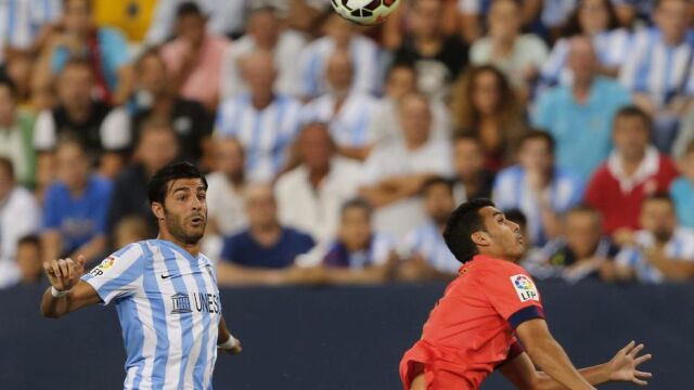El defensa del Málaga CF, Miguel Torres (i), lucha el balón con el delantero del FC Barcelona, Pedro Rodríguez, durante el encuentro de la quinta jornada de Liga en Primera División que se disputa esta noche en el estadio de La Rosaleda, en Málaga