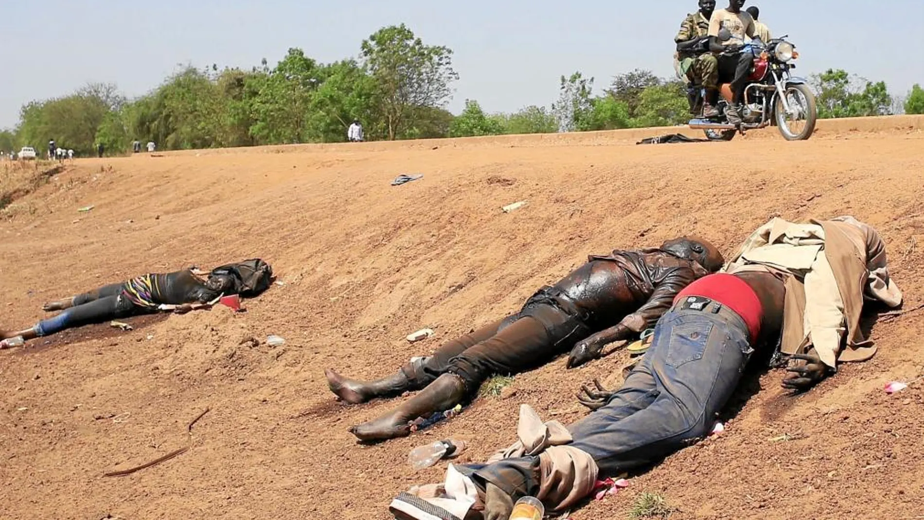 Unos rebeldes fieles a Machar pasan junto a los cadáveres en la cuneta de la carretera hacia el aeropuerto de Bor, a 180 kilómetros de la capital, Yuba