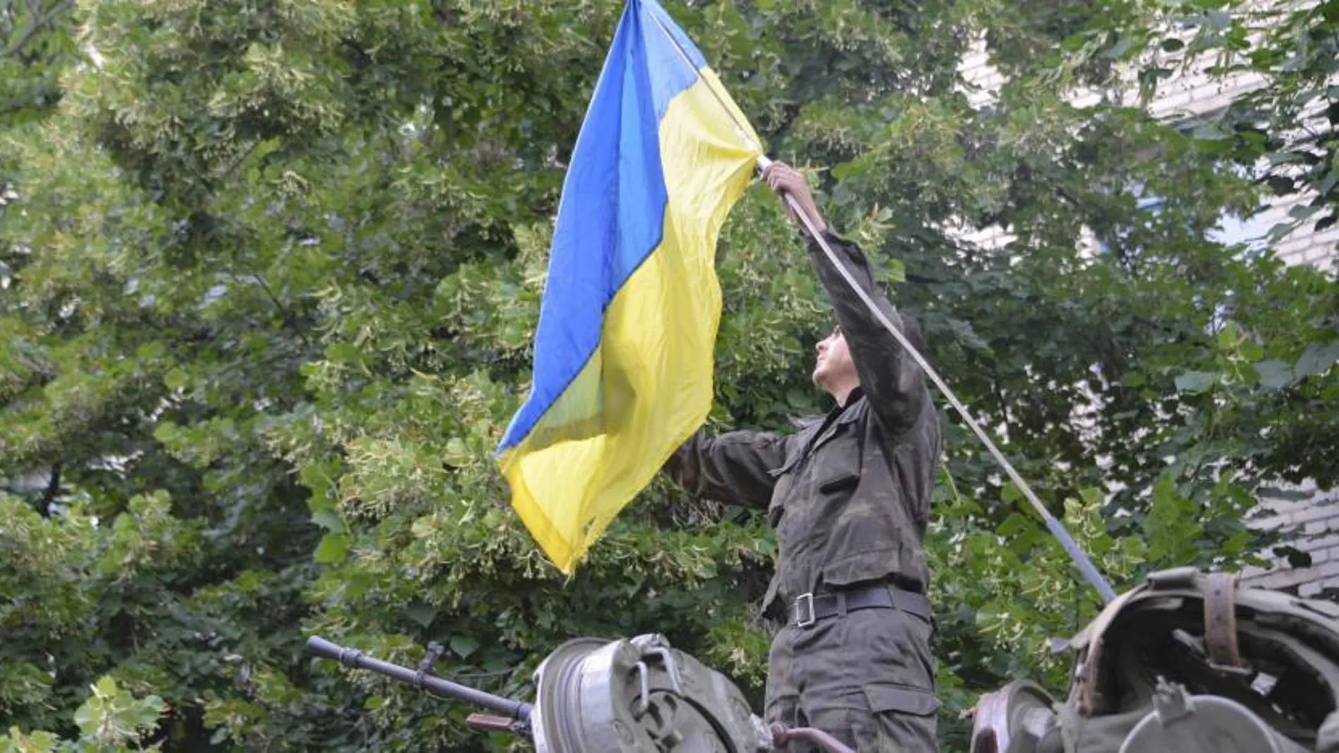 Un soldado ucraniano coloca la bandera de Ucrania en su vehículo militar en el centro de Slaviansk.