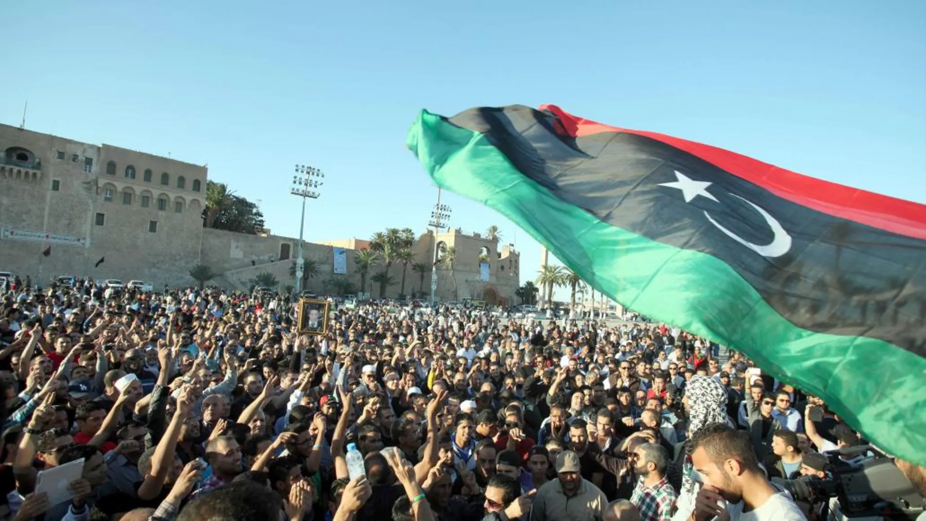 Libios ondean su bandera durante el funeral de unos manifestantes asesinados durante una protesta, en Trípoli hace casi dos años