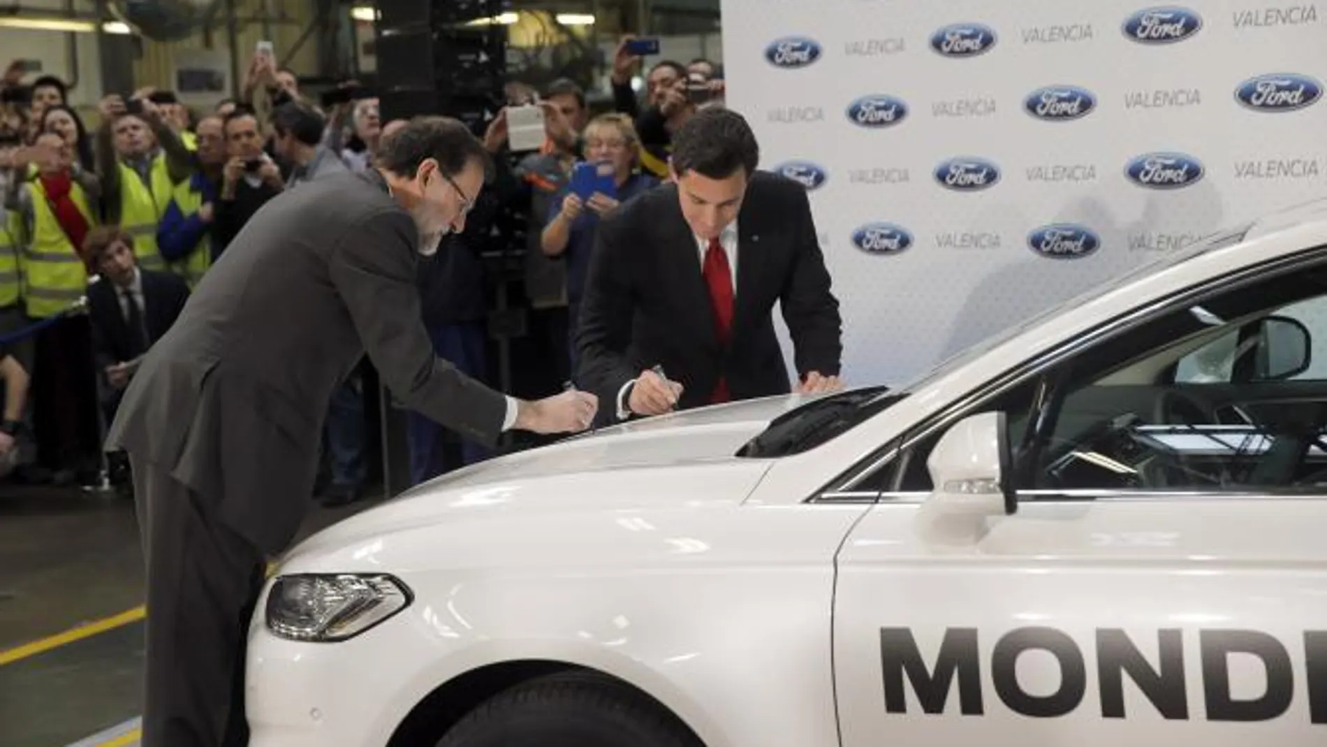 El presidente del Gobierno y el presidente mundial de Ford firman sobre un vehículo durante la visita la fábrica de Ford en Almussafes