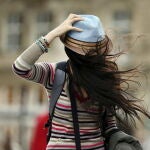 Una mujer se sostiene el sombrero mientras lucha contra el viento en Colonia (Alemania)