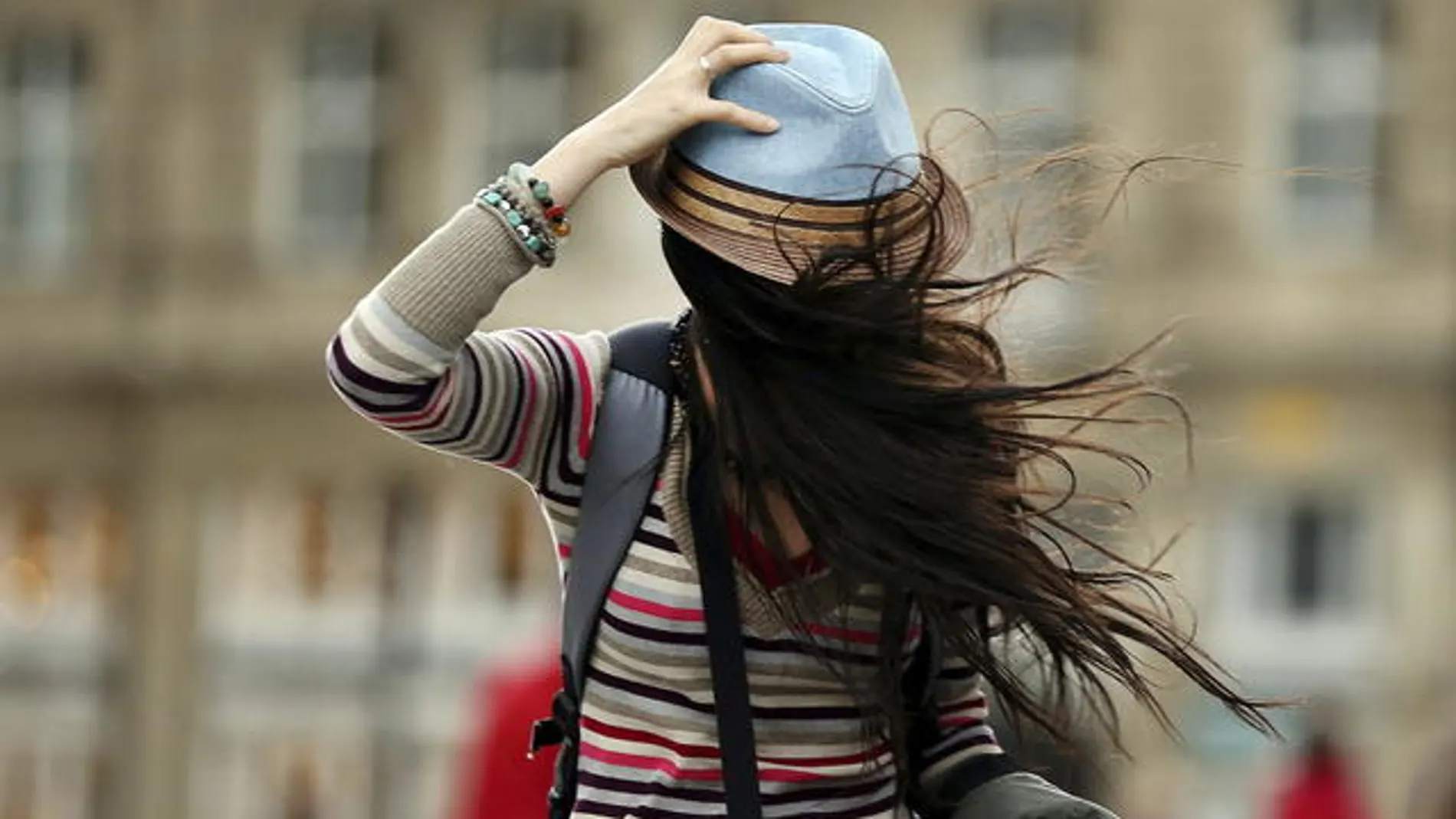 Una mujer se sostiene el sombrero mientras lucha contra el viento en Colonia (Alemania)