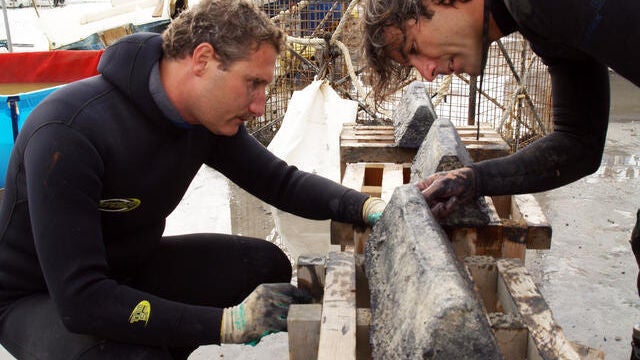 Buzos junto a un lingote extraído del agua