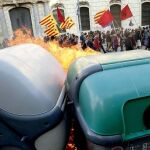 Participantes en una manifestación alternativa convocada esta tarde en Barcelona con motivo del 1 de mayo pasan ante contenedores ardiendo.