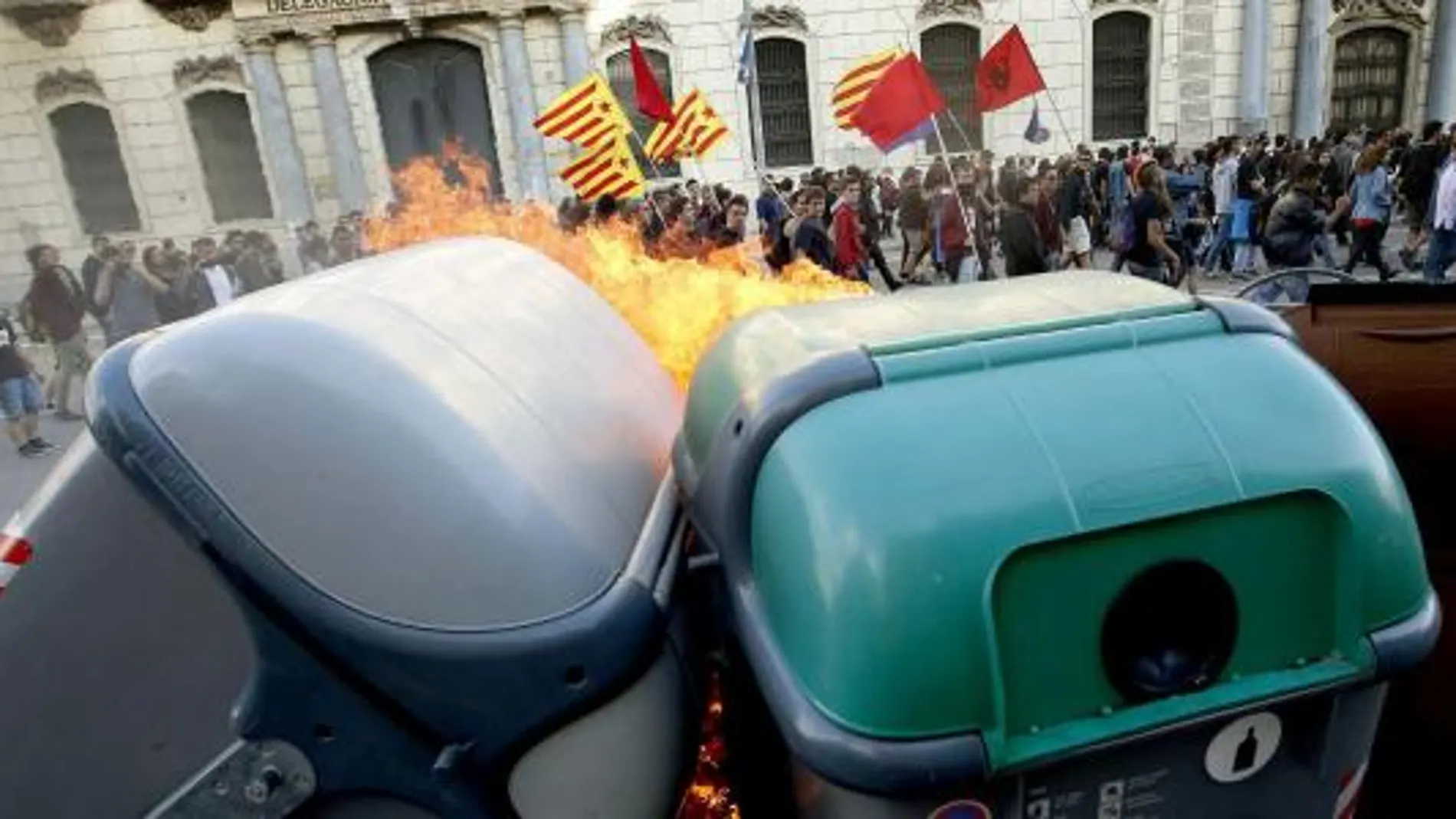 Participantes en una manifestación alternativa convocada esta tarde en Barcelona con motivo del 1 de mayo pasan ante contenedores ardiendo.