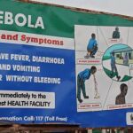 Un cartel en una calle de Freetown, en Sierra Leona, explica los síntomas del ébola