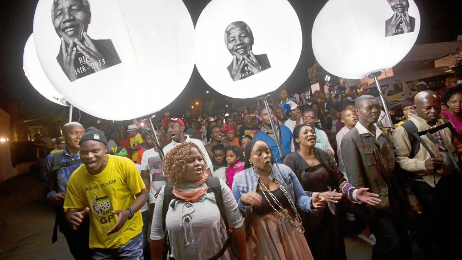 TRIBUTO GLOBAL. Varios ciudadanos marchan frente la casa de Mandela en Soweto, Johannesburgo