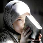 Una pequeña sostiene en sus manos el Corán
