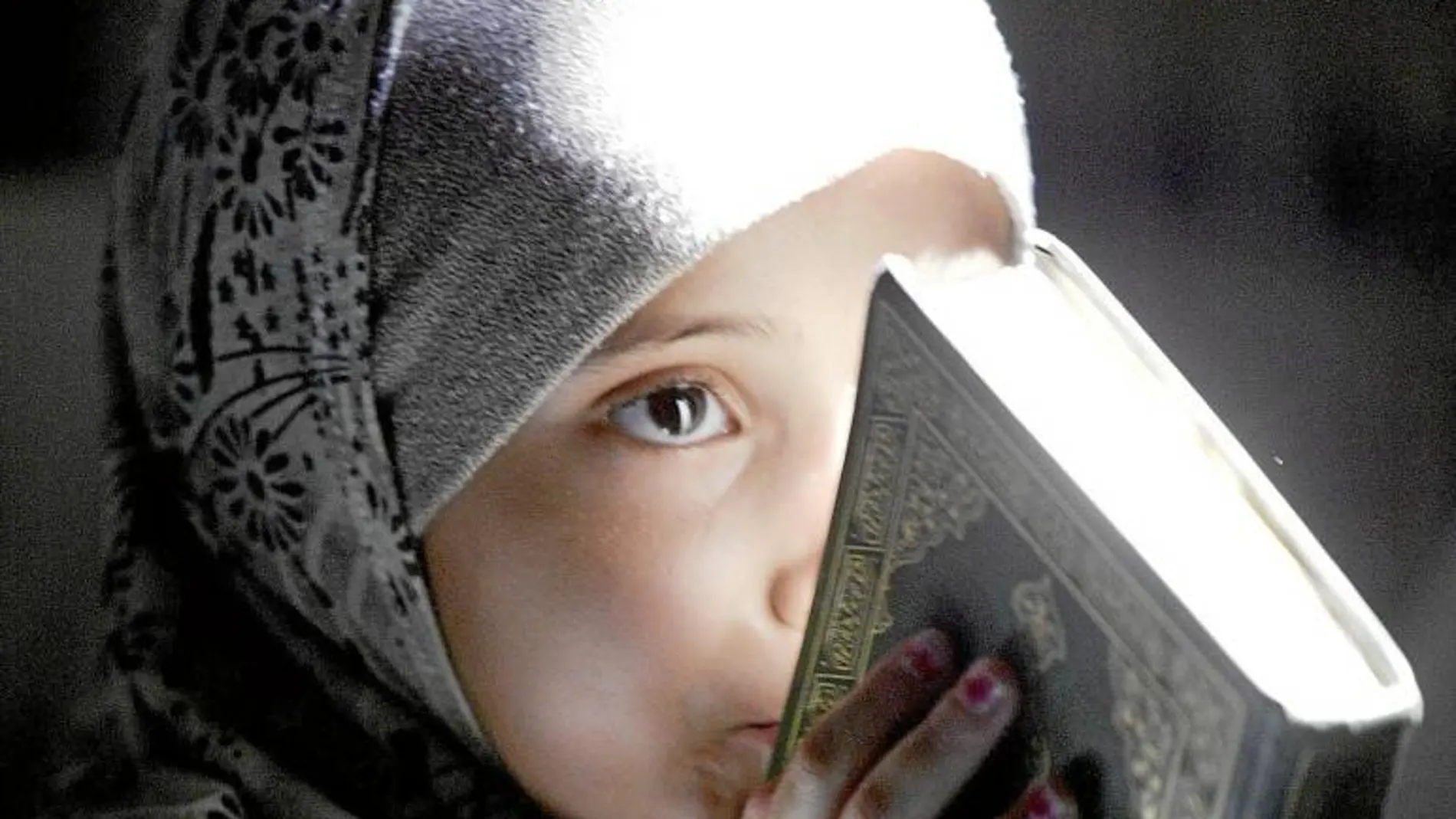 Una pequeña sostiene en sus manos el Corán