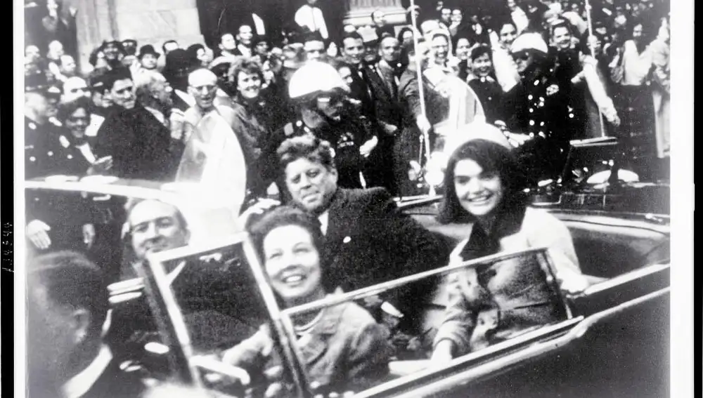 John y Jackie Kennedy sonríen a la cámara durante su paseo por las calles de Dallas, minutos antes del magnicidio