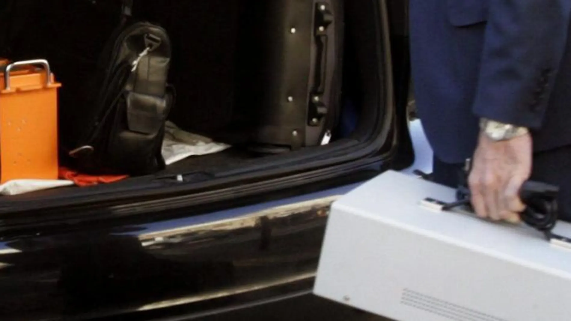 Técnicos y policía científica guardan en el maletero de un coche la caja negra (de color naranja) del tren siniestrado