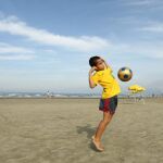 Un niño juega con una pelota en una playa de Brasil