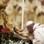 El Papa besa la estatua del Niño Jesús durante la misa de Nochebuena