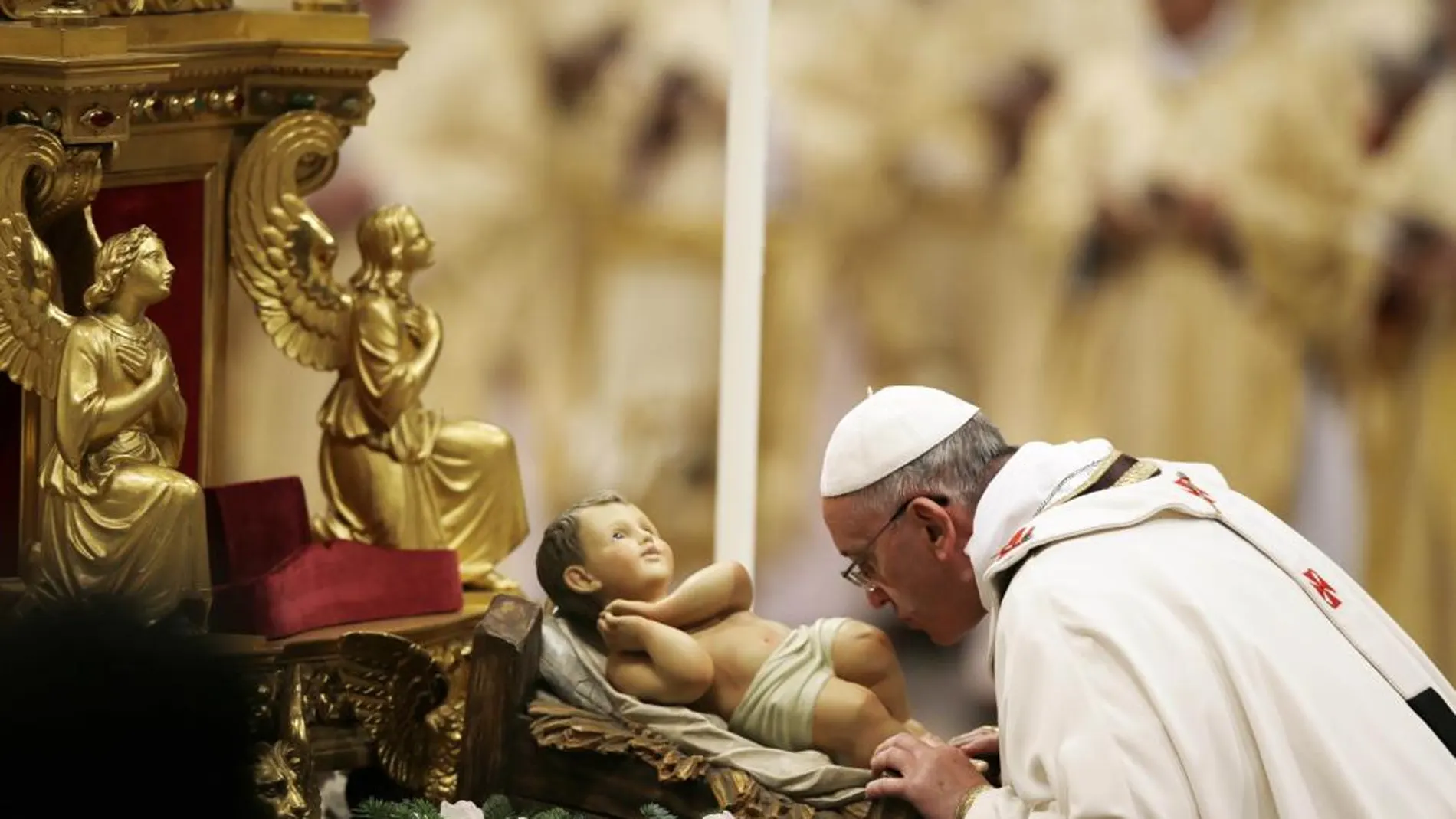 El Papa besa la estatua del Niño Jesús durante la misa de Nochebuena