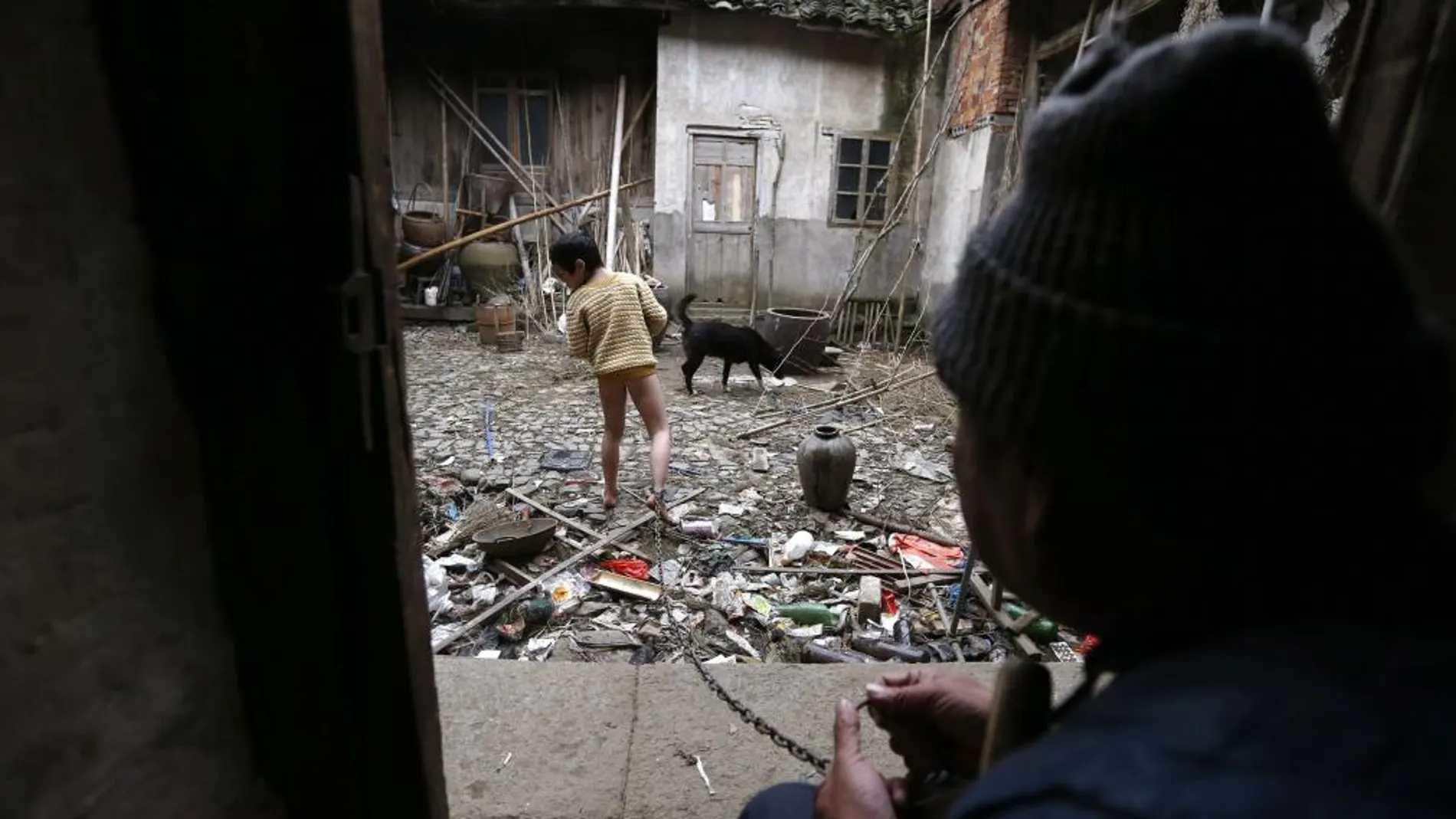 Zili busca entre la basura de un patio cercano a su casa, ante la atenta mirada de su abuelo