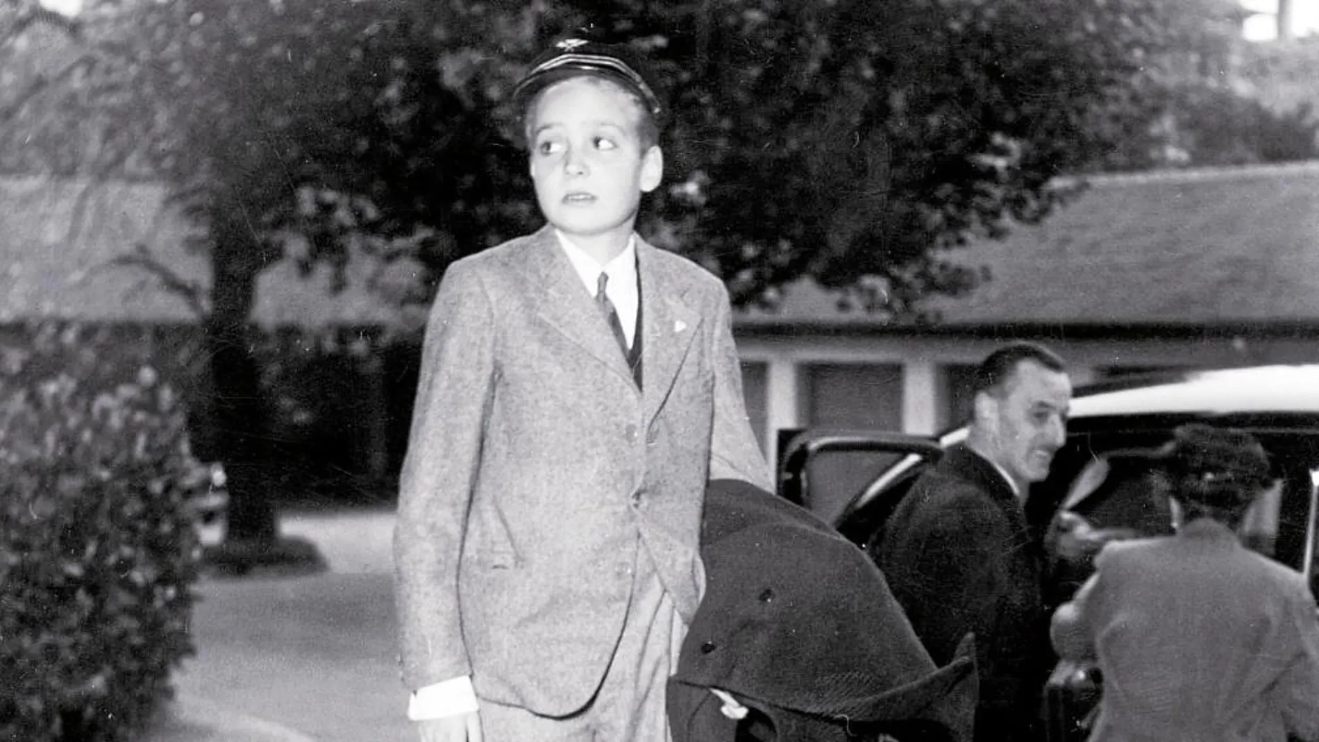 La primera vez que Don Juan Carlos pisó España tenía 10 años. Previamente había residido en Suiza, donde se tomó esta fotografía en 1958, en la que espera a montar en el coche que le llevaría al aeropuerto para coger un avión con destino a Portugal. De ahí se trasladó a España.