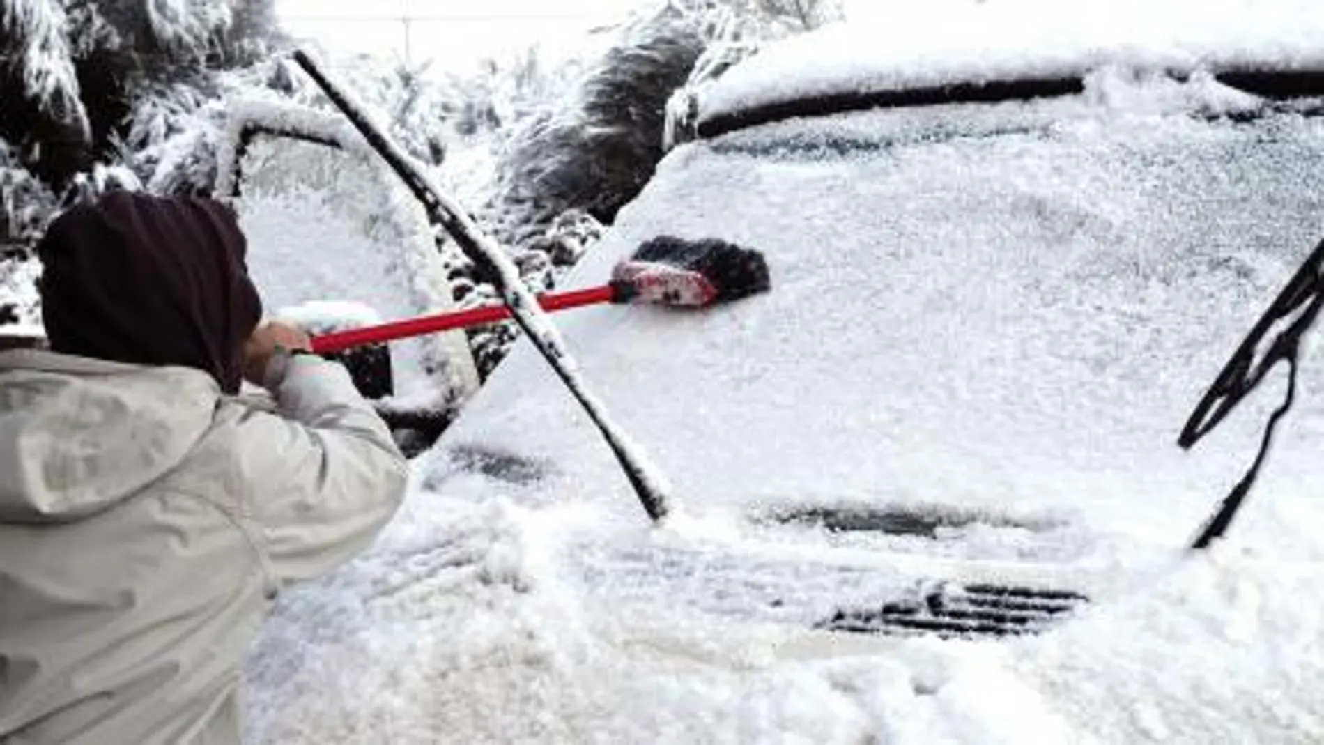 Una persona retira la nieve y el hielo de su coche en Lugo