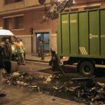 Un camión retira uno de los tres contenedores que tres personas encapuchadas han prendido fuego hoy en el barrio bilbaíno de Santutxu.