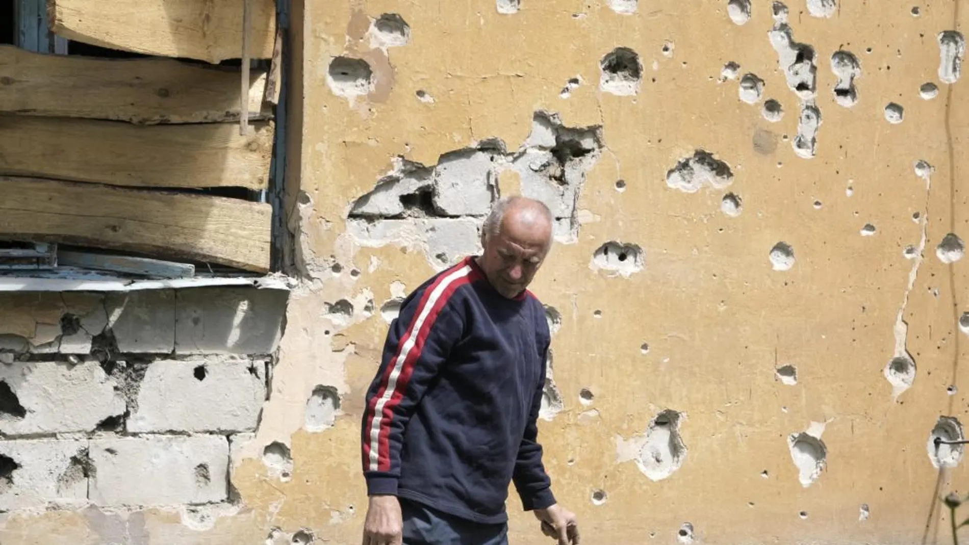 Un hombre permanece junto a una casa dañada en un bombardeo en el distrito Kieviskiy de Donetsk