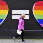 Una mujer pasea frente a un grafiti a favor de los enlaces gays