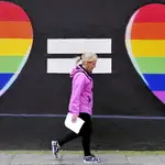 Una mujer pasea frente a un grafiti a favor de los enlaces gays
