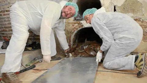Dos técnicos extraen el contenido del nicho número 1 de la cripta