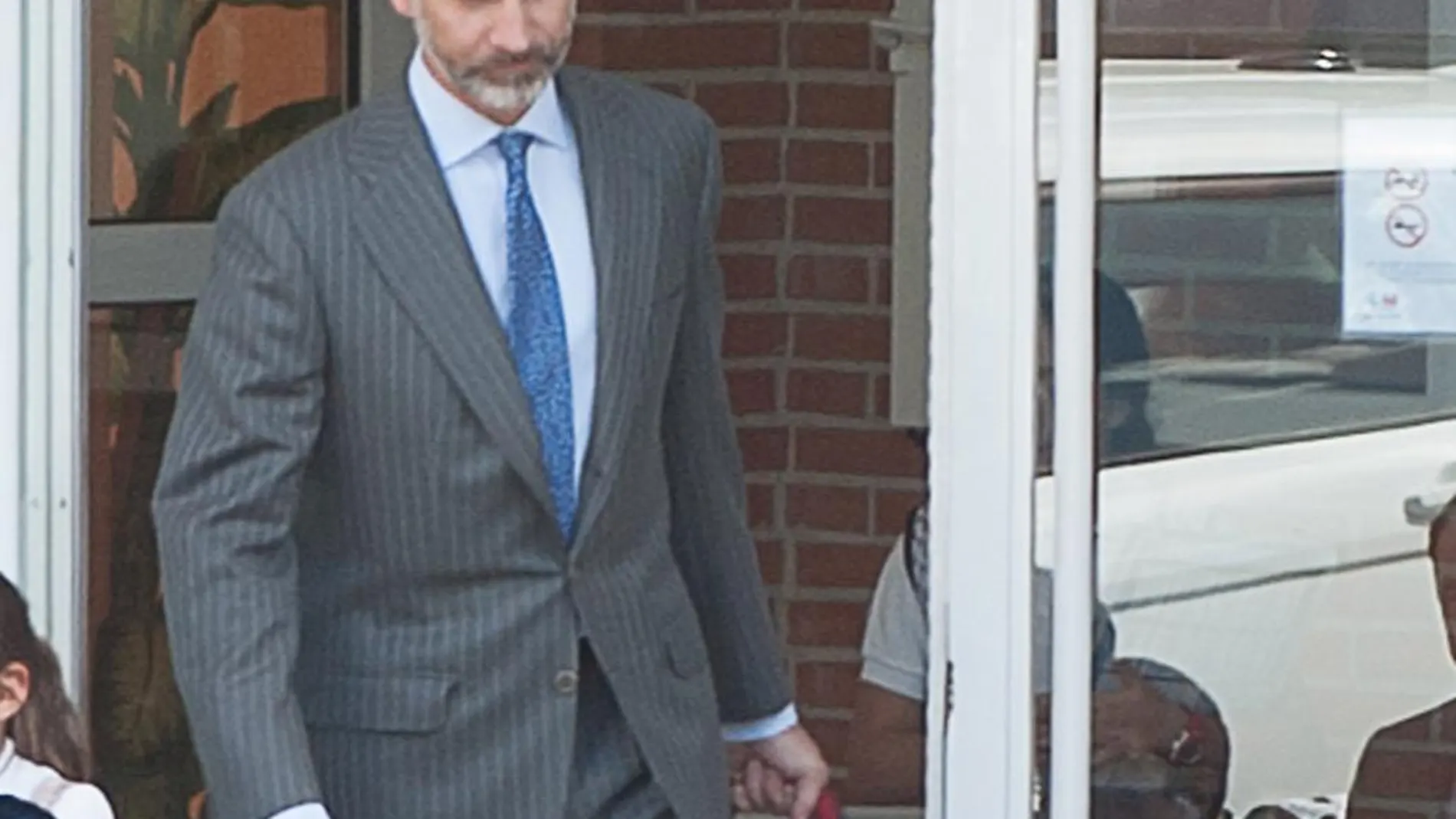 Don Felipe sale del colegio con las mochilas de sus hijas