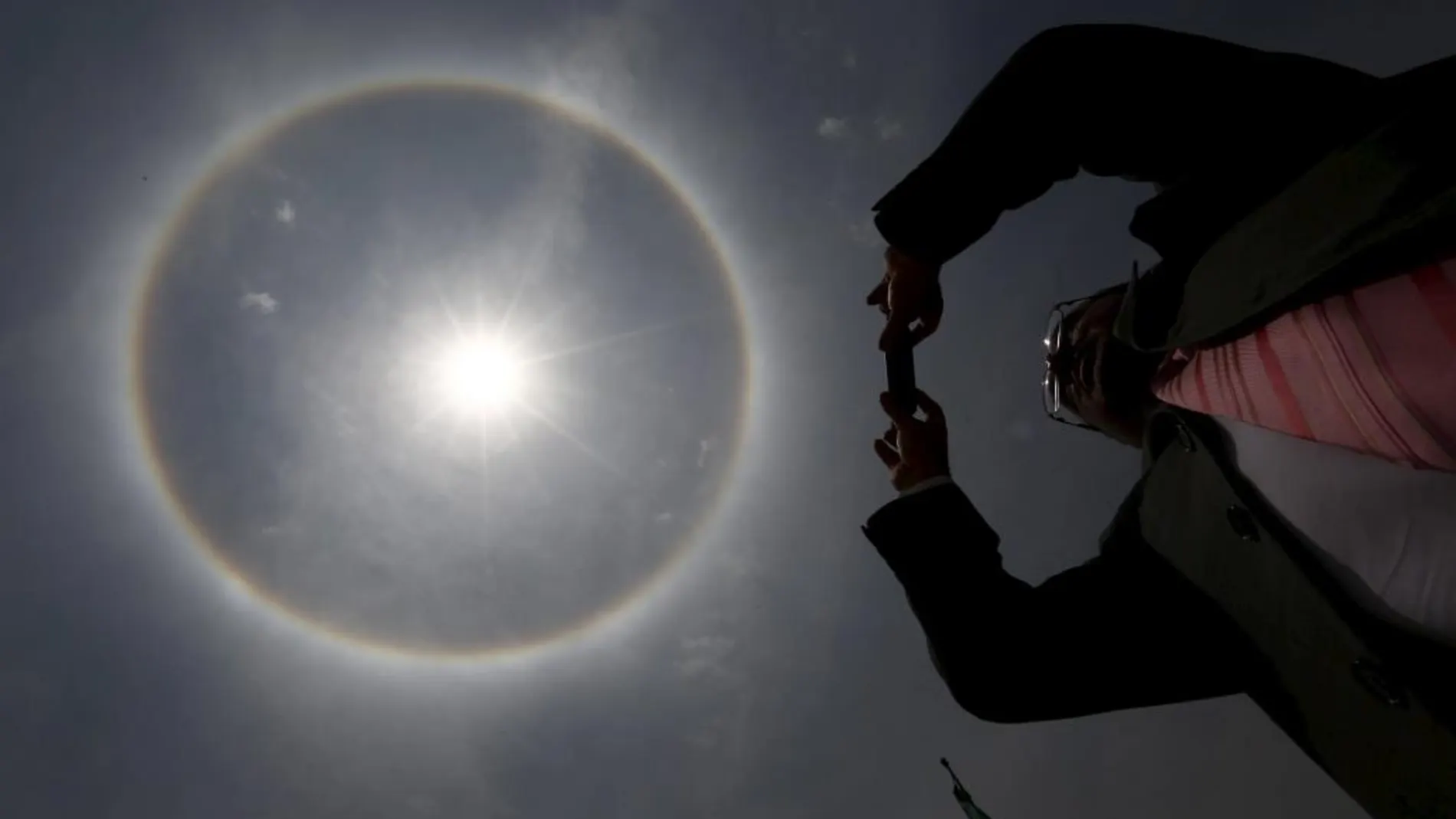 Un hombre fotografía el halo solar visible en la ciudad de México este jueves