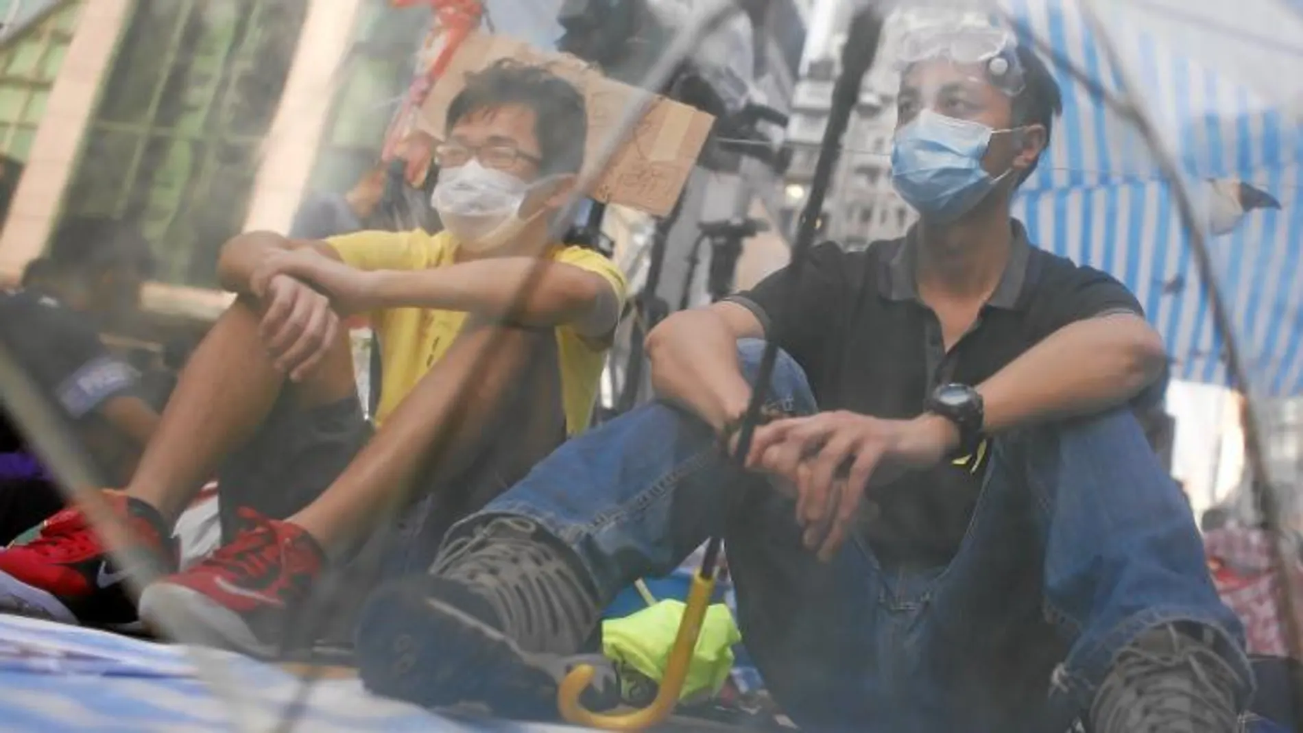 Dos activistas prodemocracia se protegen de un posible ataque de la Policía con un paraguas, en Hong Kong