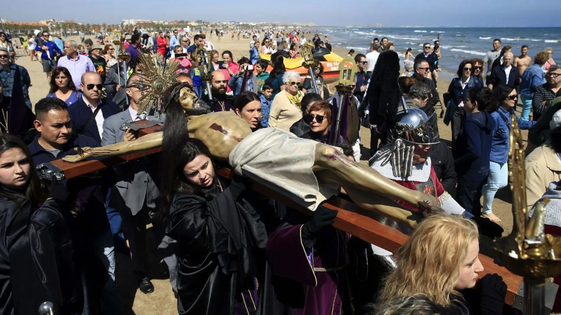 Miembros de las distintas cofradías y público se mezclan en Viernes Santo durante la procesión a la playa de la Semana Santa Marinera para honrar a los muertos en el mar. Imagen de archivo.