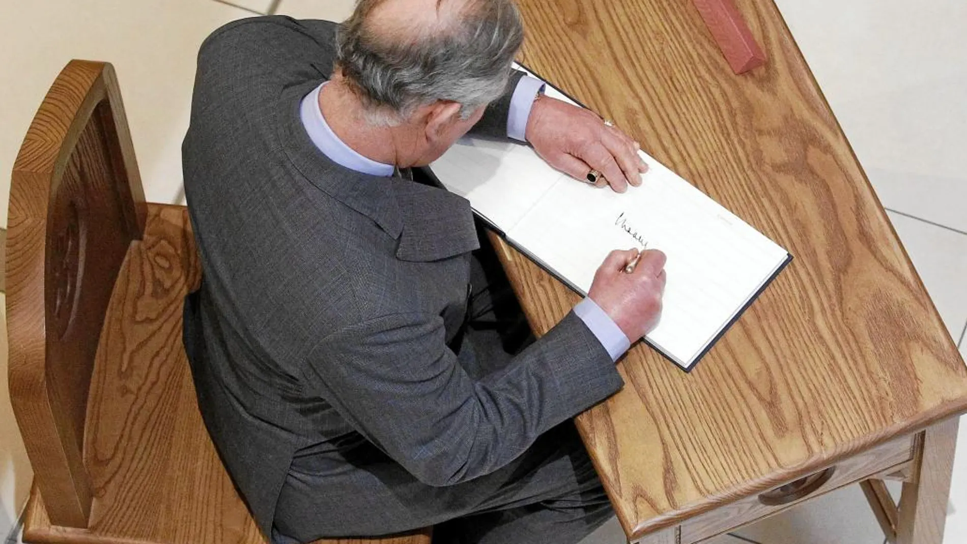 Carlos firma en el libro de visitas durante una visita oficial a un cuartel en Belfast