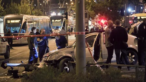 Policías israelíes examinan un vehículo en el lugar donde éste embistió a un grupo de personas, lo que se cree fue un ataque terrorista, en Jerusalén.