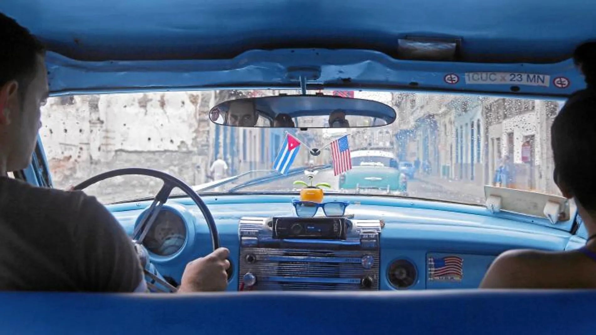 Un coche con las banderas de Cuba y Estados Unidos adheridas al parabrisas avanza por una de las calles de La Habana
