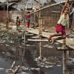 Unos niños juegan junto a las aguas estancadas en Bangladesh