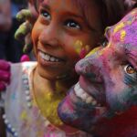 Lugareños y turistas cubiertos de polvos de colores disfrutan del Festival Holi en Calcuta (India)