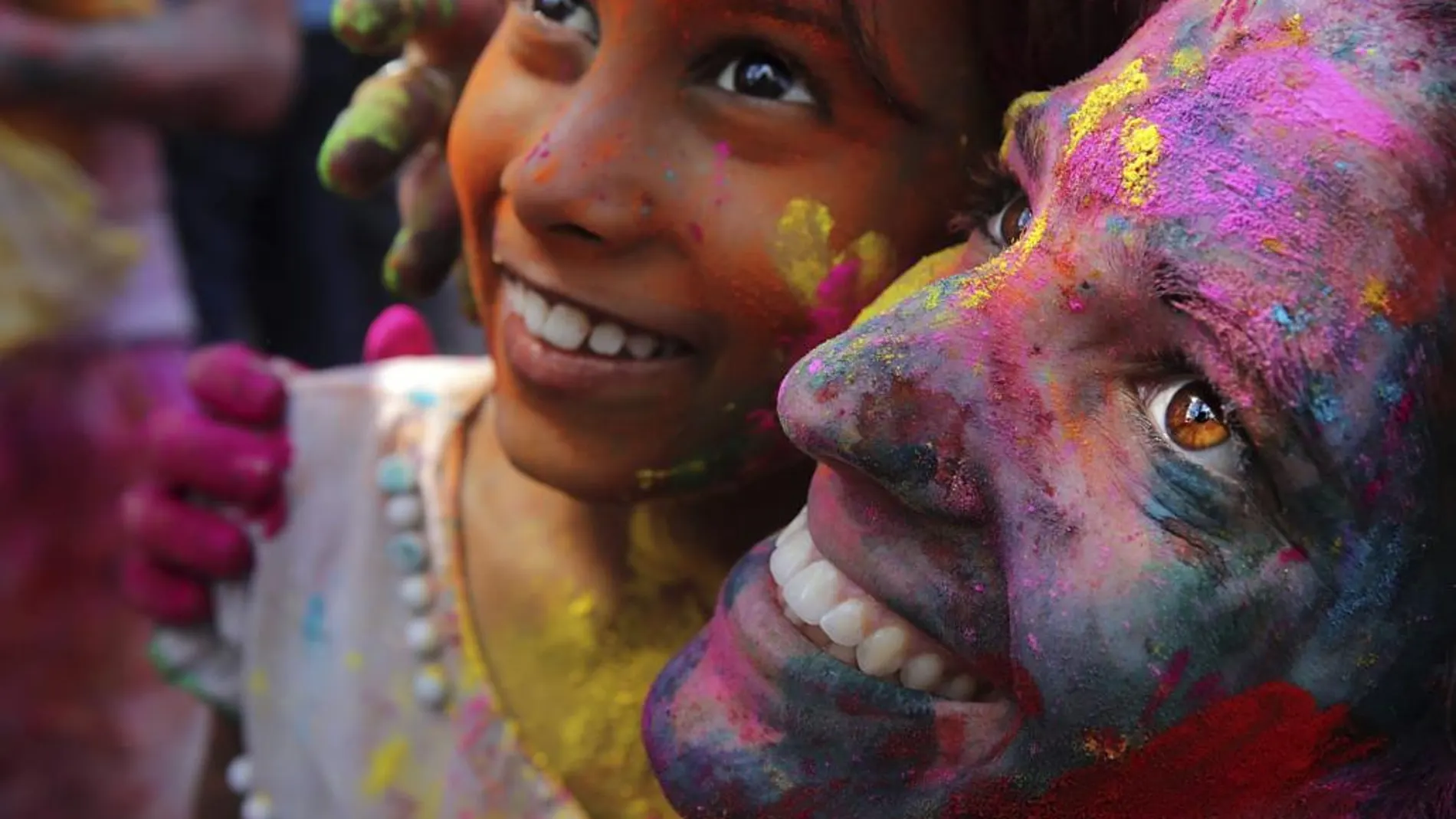 Lugareños y turistas cubiertos de polvos de colores disfrutan del Festival Holi en Calcuta (India)