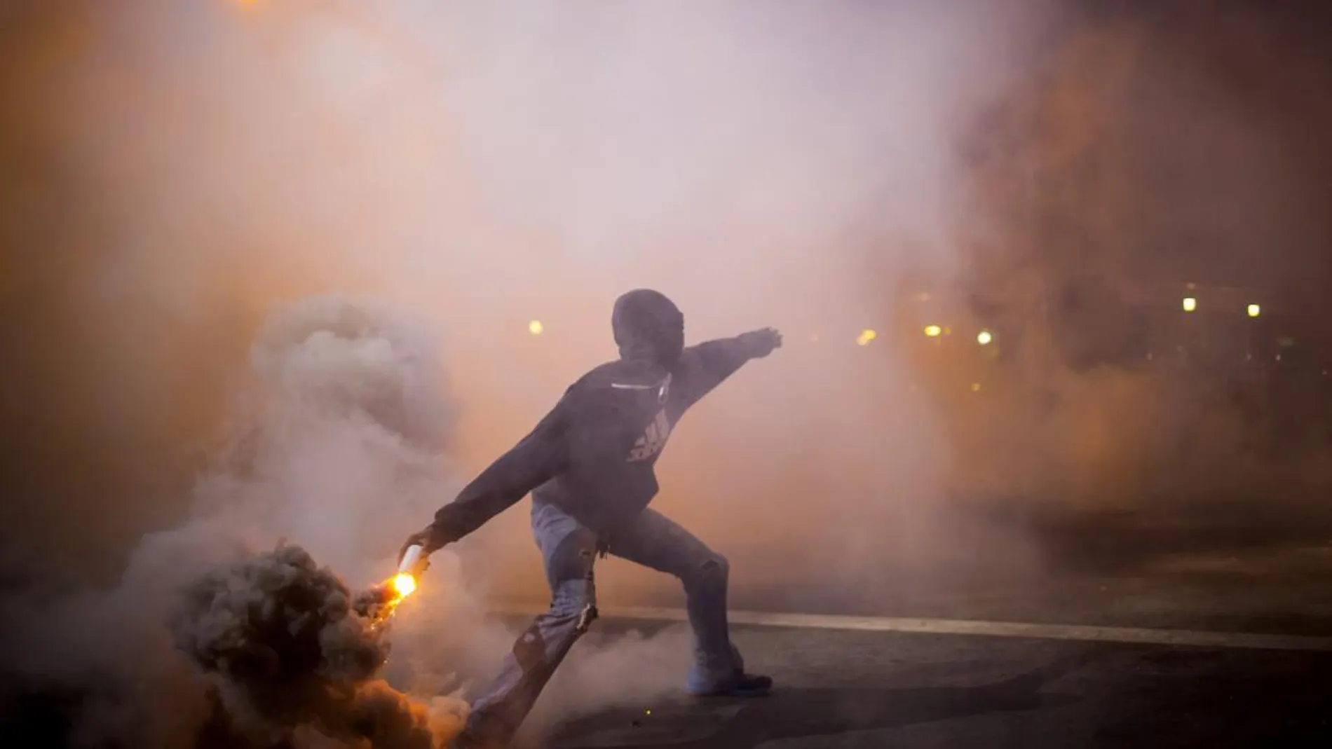 Un manifestante tira un bote de gas lacrimógeno arrojado por la policía en Baltimore