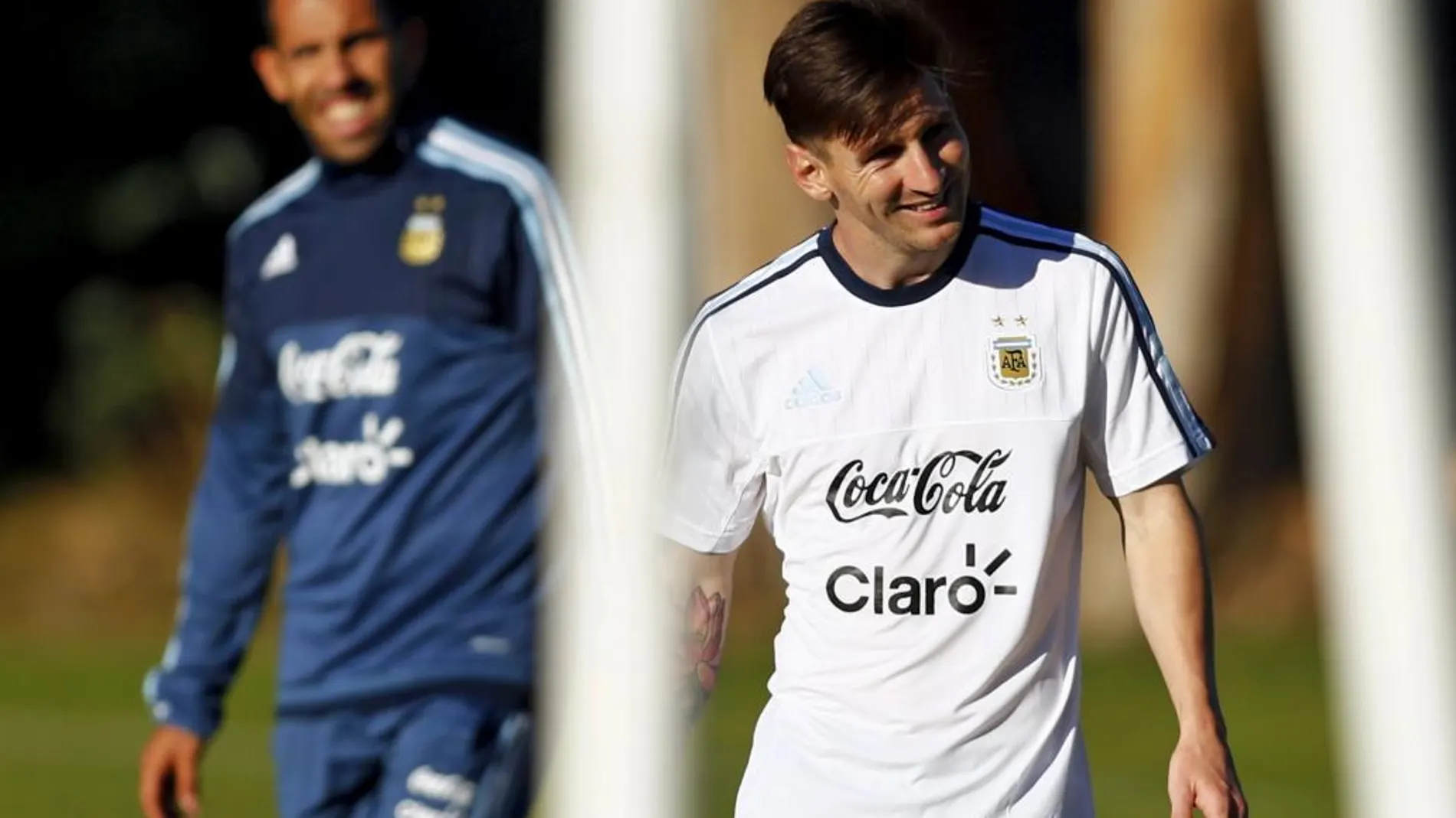 Lionel Messi sonríe mientras camina por delante de su compañero de selección Carlos Tévez