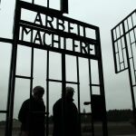 Dos personas pasan por la puerta del campo de concentración de Auschwitz