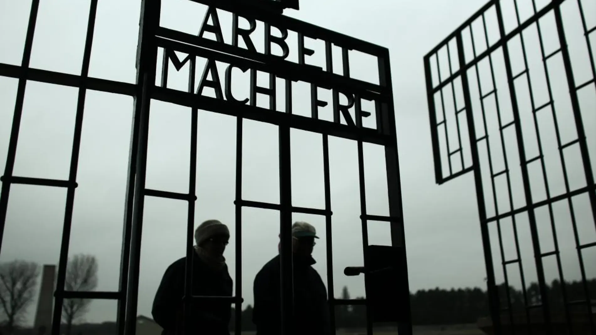 Dos personas pasan por la puerta del campo de concentración de Auschwitz