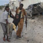 Un hombre herido es evacuado de la zona en la que se ha registrado la explosión de un coche bomba, en Mogadiscio, Somalia