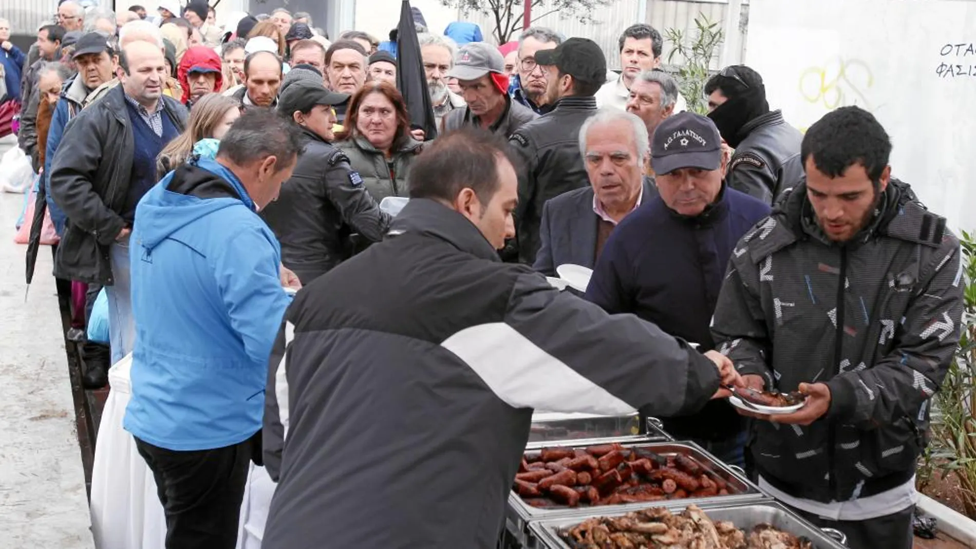 Un grupo de griegos hace cola para conseguir alimentos en un comedor social de Atenas