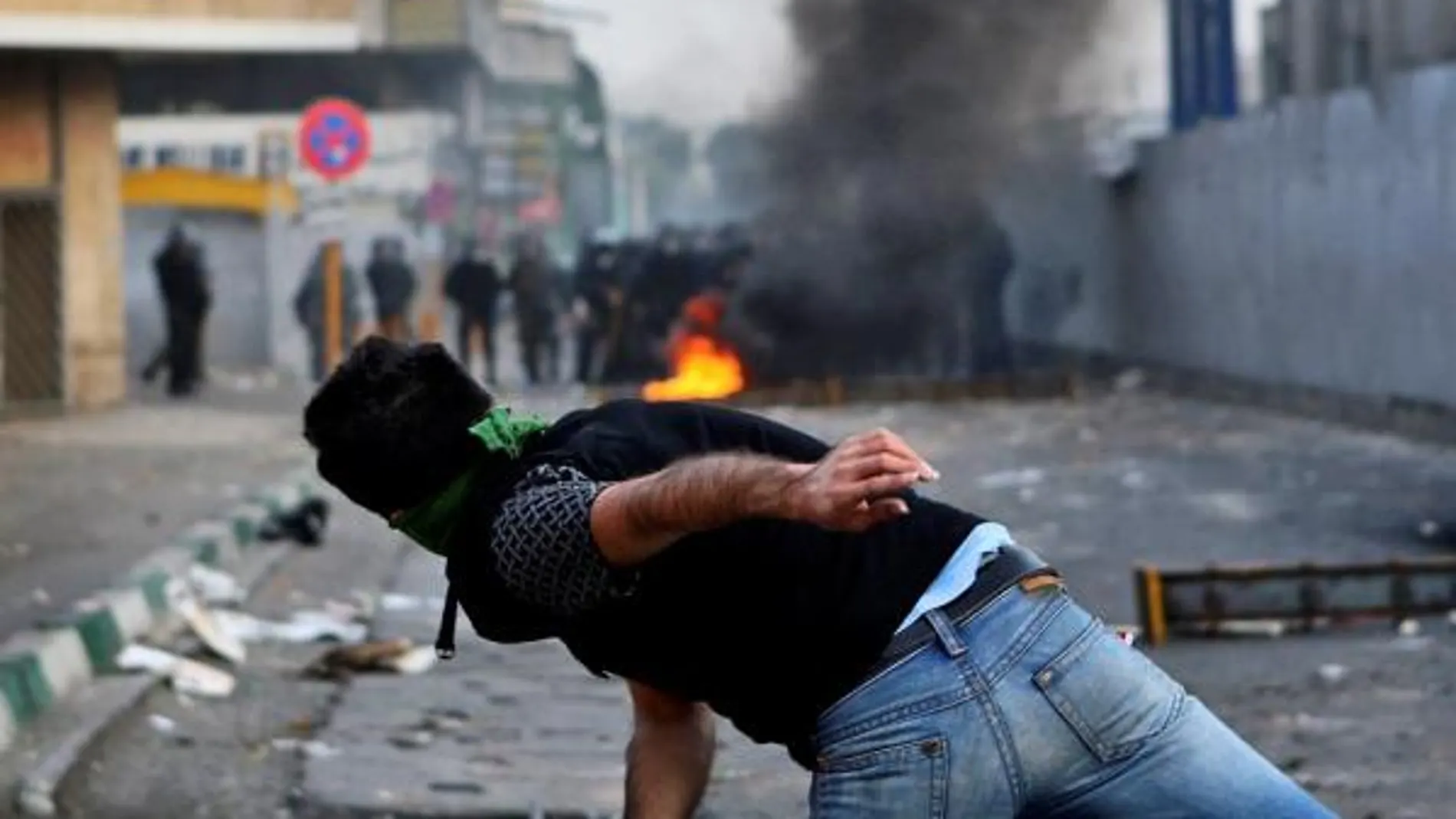 Un manifestante lanza una piedra contra la Polícía en el centro de Teherán el pasado sábado