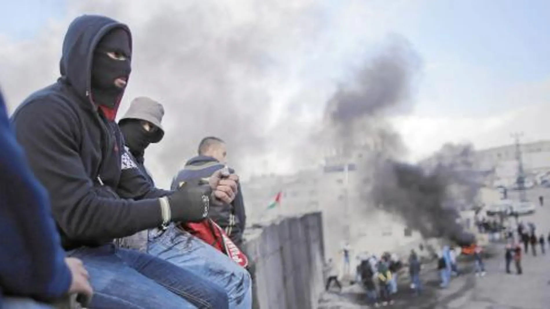 Manifestantes palestinos encaramados al muro que separa la ciudad de Abu Dis de Jerusalén