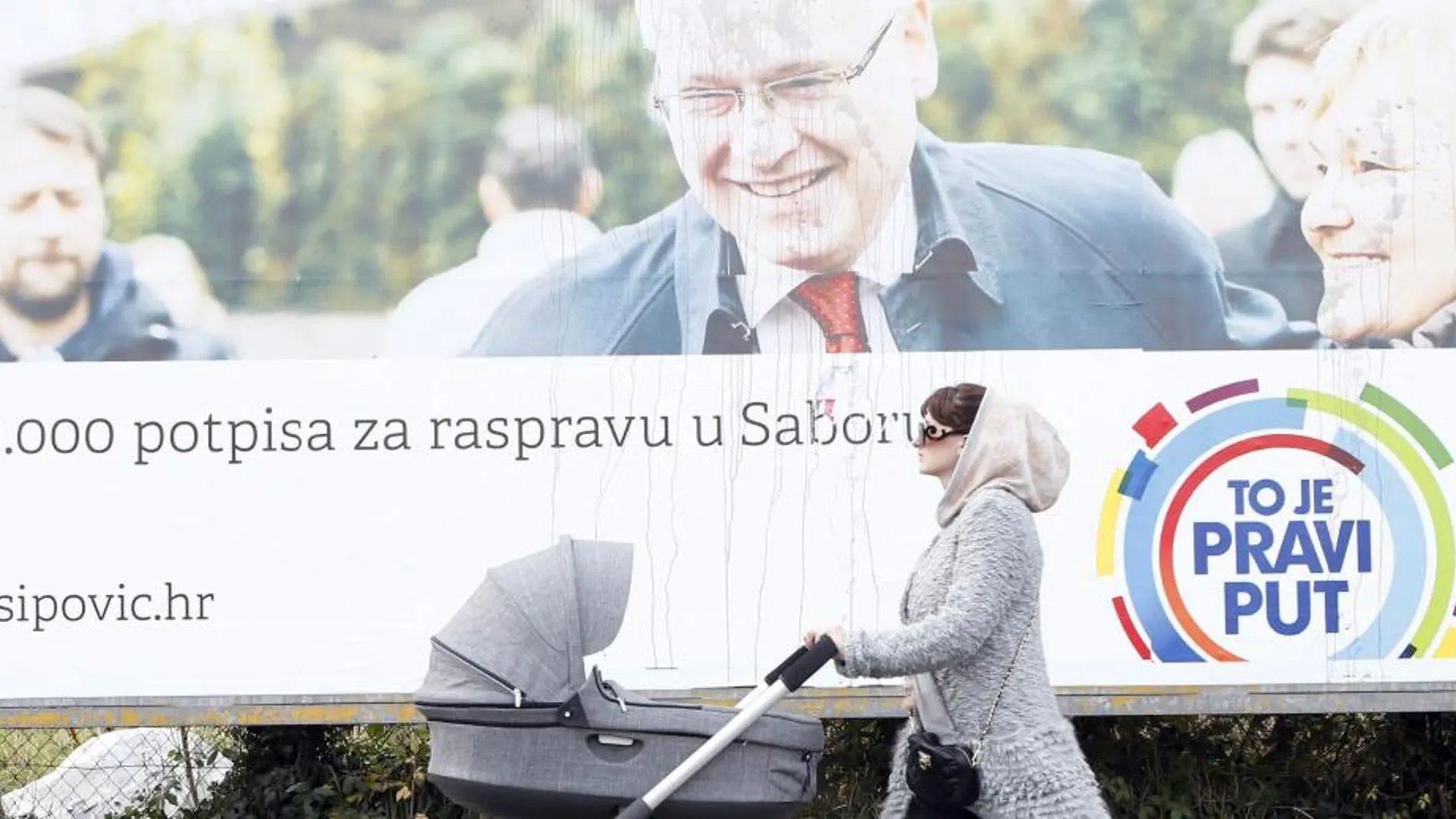 Una mujer pasea a su bebé frente a un cartel a favor del actual presidente de Croacia, Ivo Josipovic.