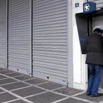 Un ciudadano griego saca dinero ayer en un cajero de Atenas