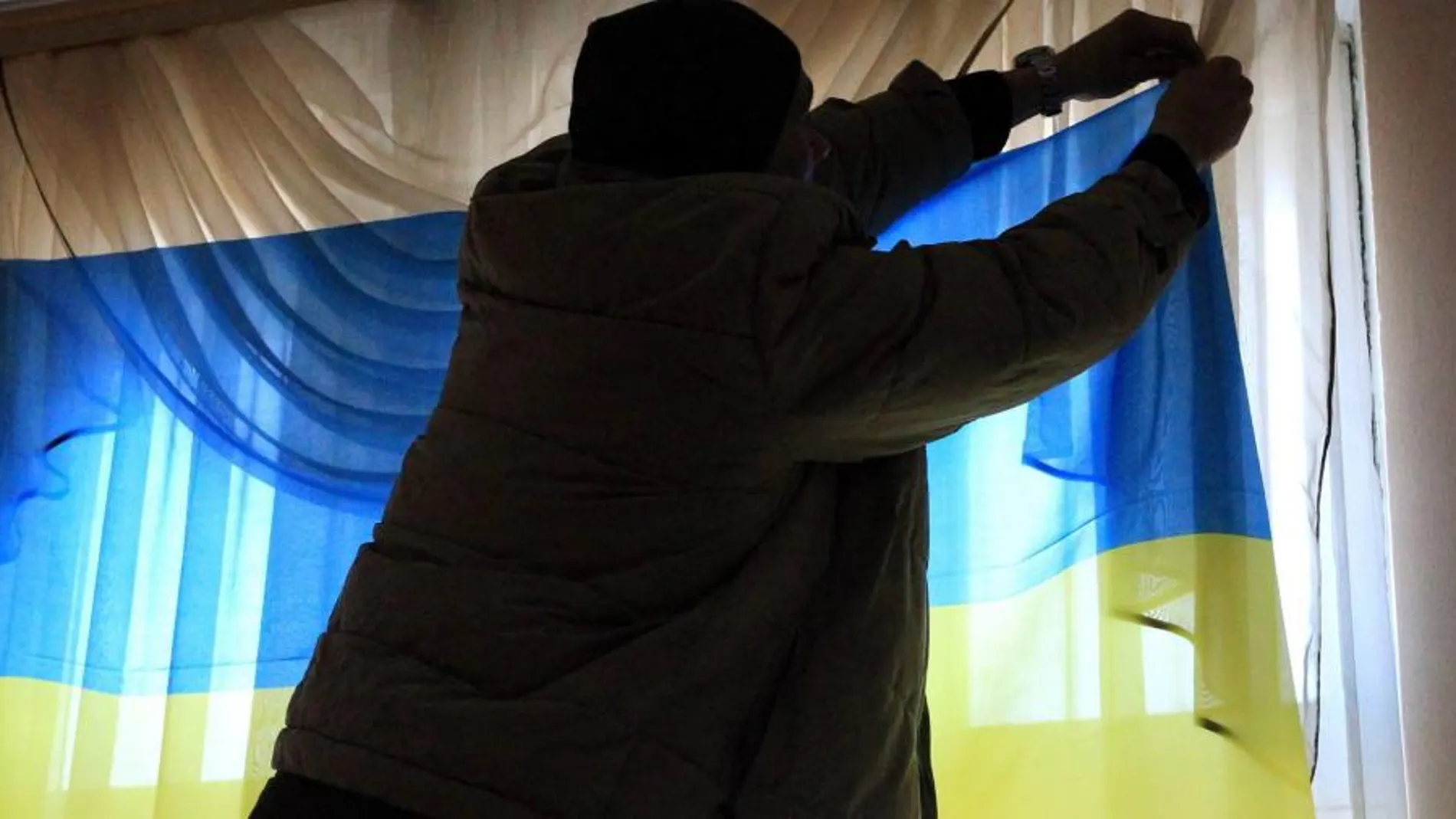 Un miembro de la comisión electoral cuelga una bandera ucraniana en Kiev